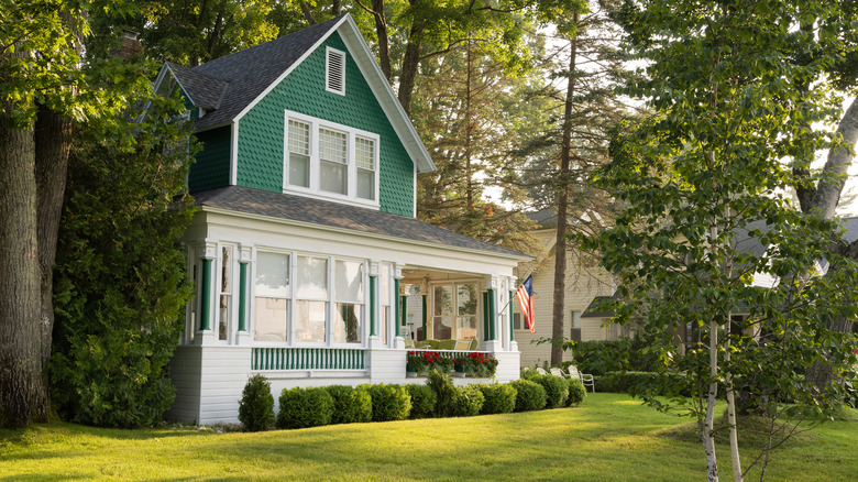 Green two-story house in a quiet neighborhood