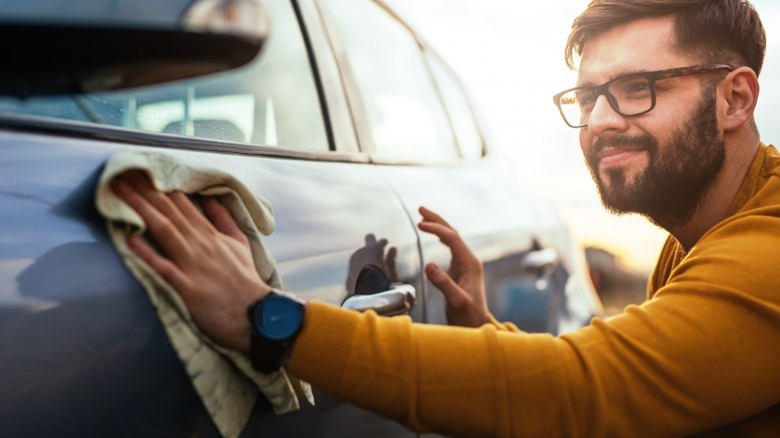 Man with glasses and beard polishing car