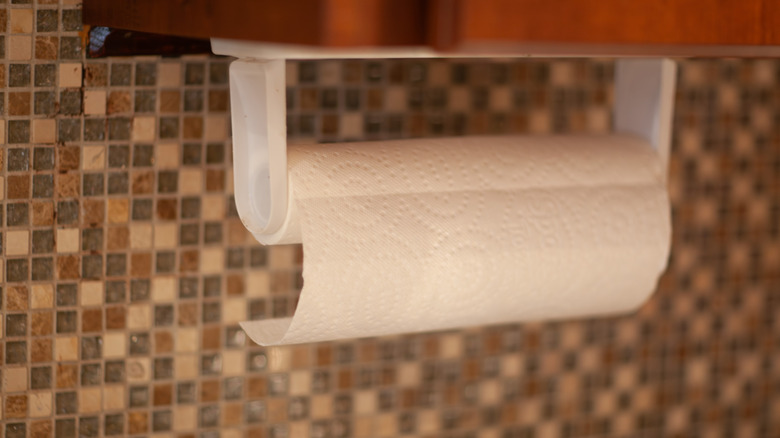 a plastic paper towel holder on a tile wall