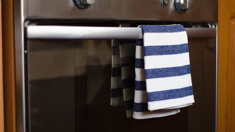 A blue and white towel hangs  from an oven door handle
