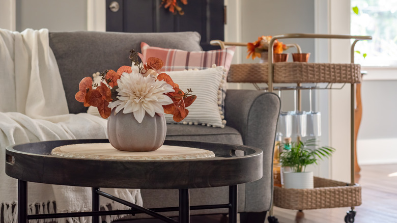 Grey couch with gold-toned bar cart and small coffee table