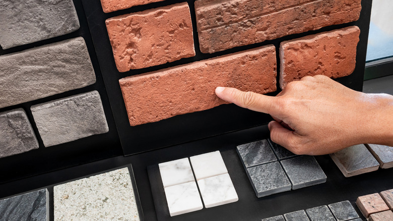 Hand points to a brick sample in a store.