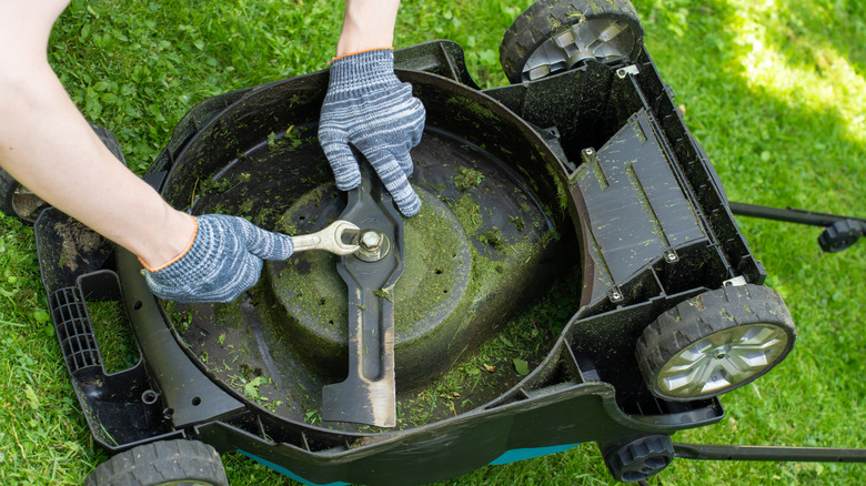 Person working with a wrench to remove a mower blade