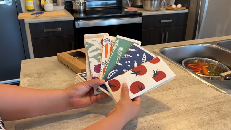 Woman holding an array of Swedish dishcloths