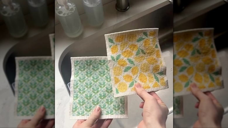 hands holding two patterned colorful Swedish dish clothes over a sink