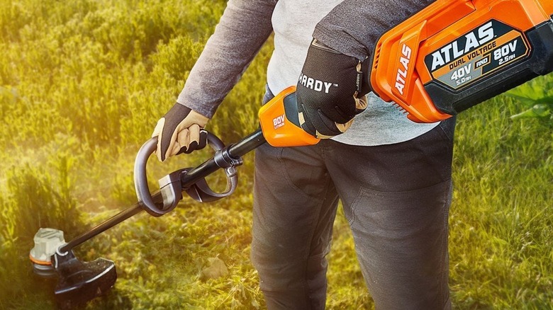 Person using Atlas string trimmer on lawn