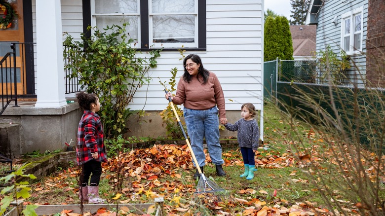 Family raking leaves in small yard