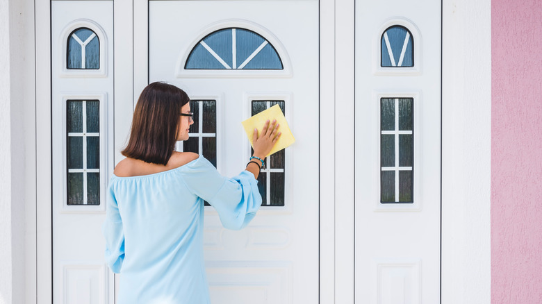 A woman cleaning a white front door