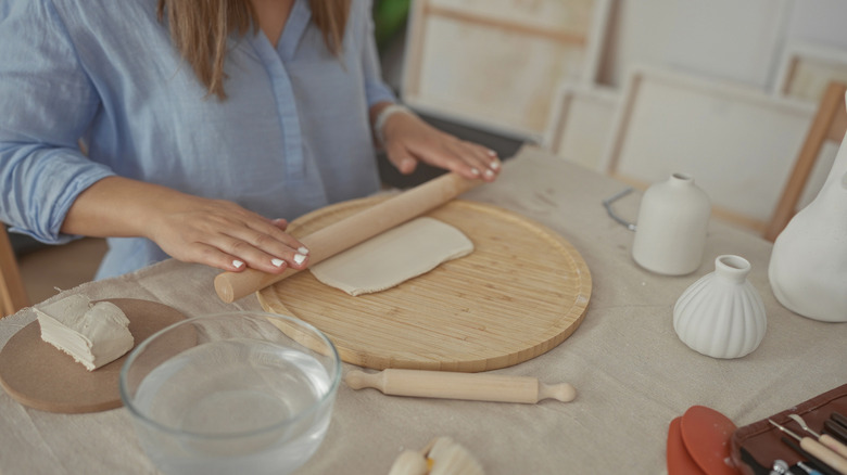 A woman rolls out clay for a project