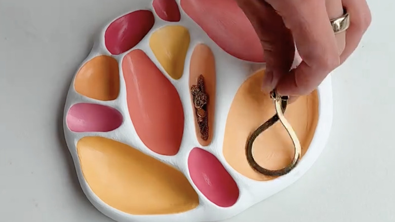 A handmade clay jewelry tray painted in red, orange and yellow.