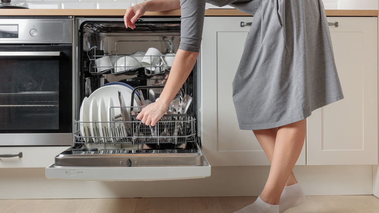 A woman loads a dishwasher.