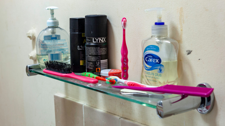 Cluttered shelf with soap, toothbrushes, brush, and deodorant