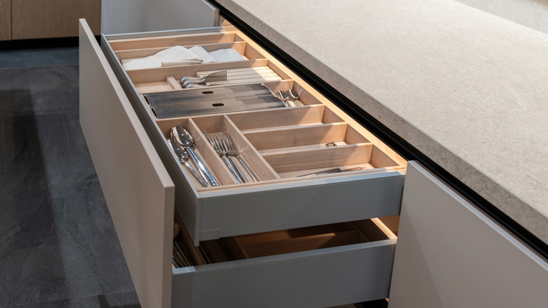 Open kitchen drawers with flatware organizing trays.