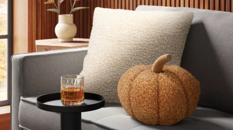 Target's orange boucle pumpkin pillow styled on a chic gray couch