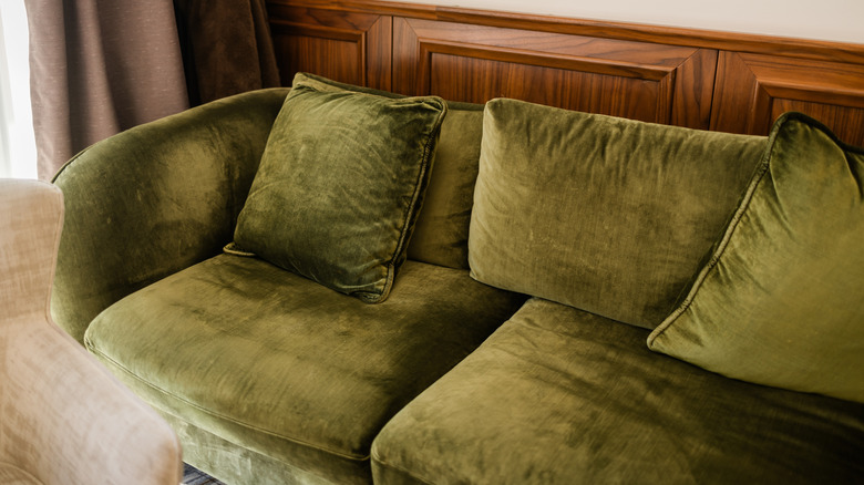 Green velvet sofa in classic interior setting