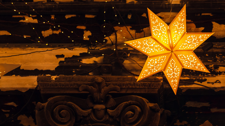 Decorative paper light in shape of a star with traditional ornaments hang on a wall in vintage room.