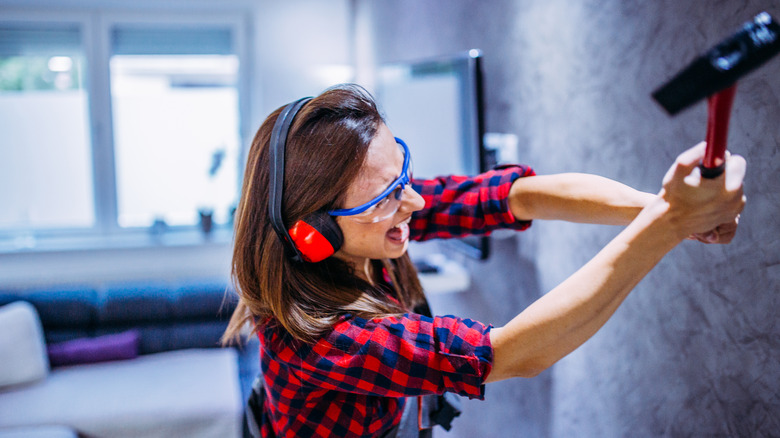 Woman hitting wall with hammer