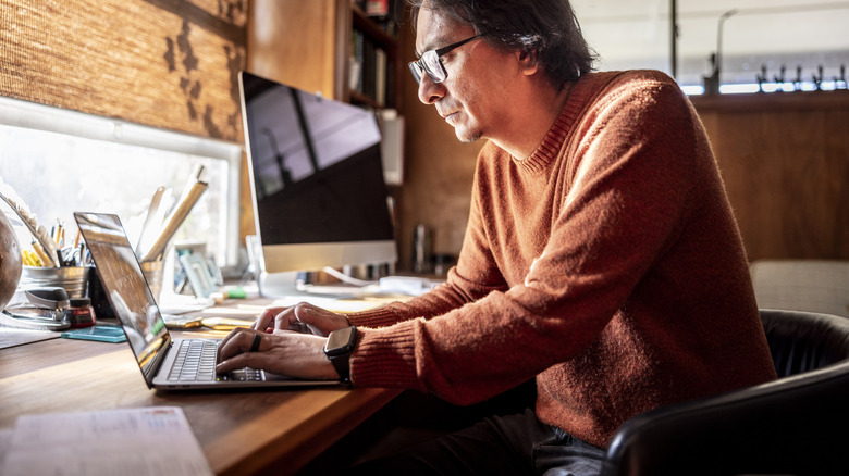 Stern looking man typing on laptop in his home office