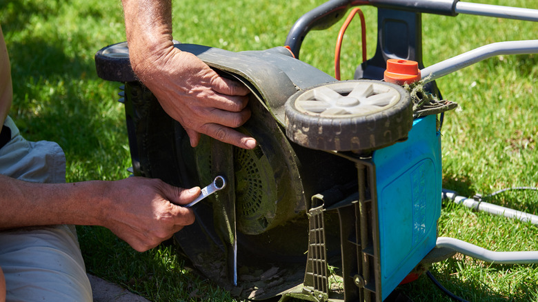 A person removing a lawn mower blade