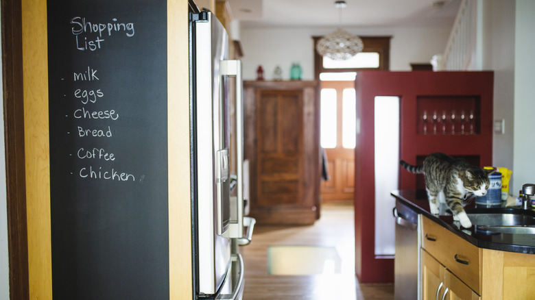 A kitchen with a chalkboard wall with groceries written down on it.