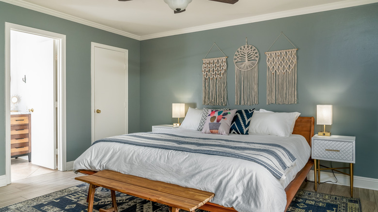 A bedroom with macrame wall art above the bed.