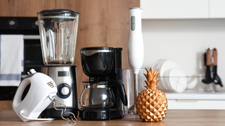 Small house appliances sitting next to a gold pineapple on counter.
