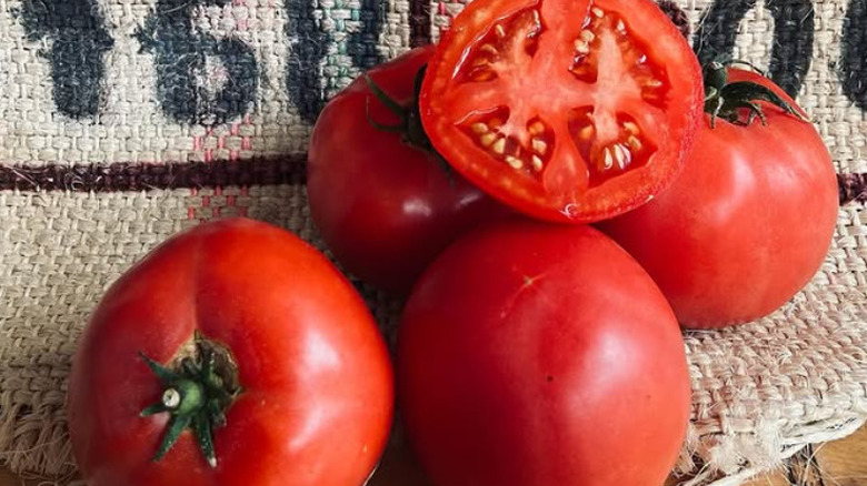 A small pile of 'Arkansas Traveler' tomatoes lay on a burlap sack with one cut down the middle.