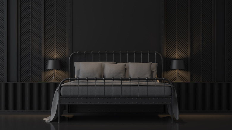 A black bedroom with an old-fashioned iron bedframe