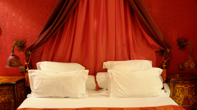 Bright red walls in a bedroom where the sheet has starkly contrasting white sheets