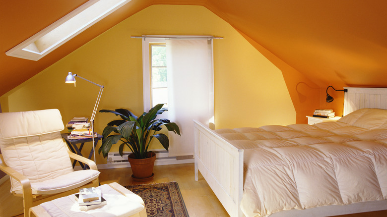 Yellow and orange walls in a bedroom with a white bed and white furniture