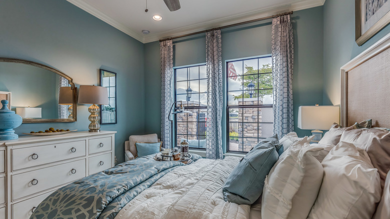 A bedroom with pale blue walls and white furniture