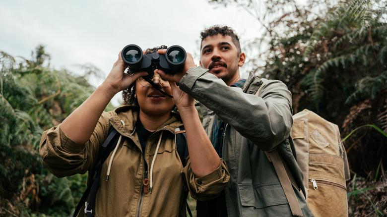 Couple birdwatching outside with binoculars