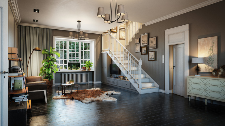 A room with black wood floors and white staircase