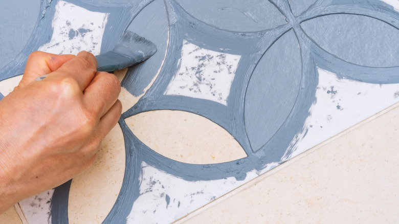 Close up of hand painting a curved stencil in light blue