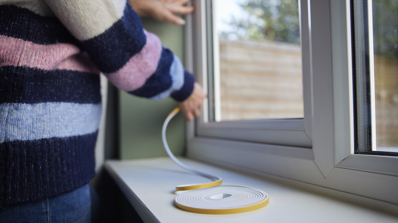 Homeowner installs window insulation kit.