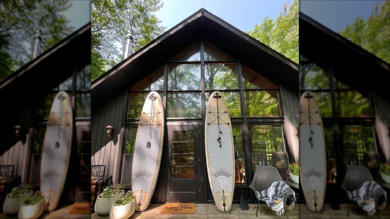 Two longboards rest against an all-black A-frame house