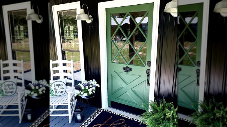 A white rocking chair and Boston fern flank a dark green front door