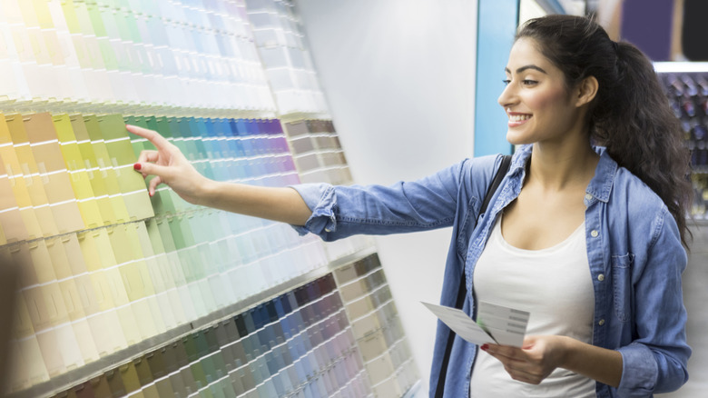 A woman smiles while looking at a paint swatch display