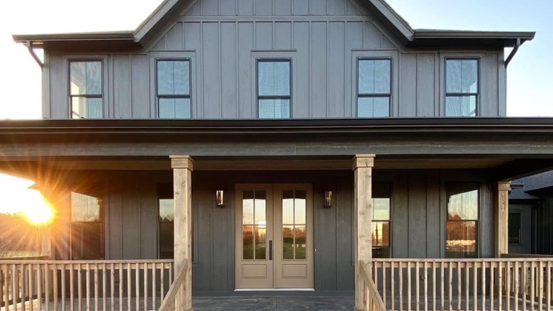 A light brown door contrasts against a black farmhouse