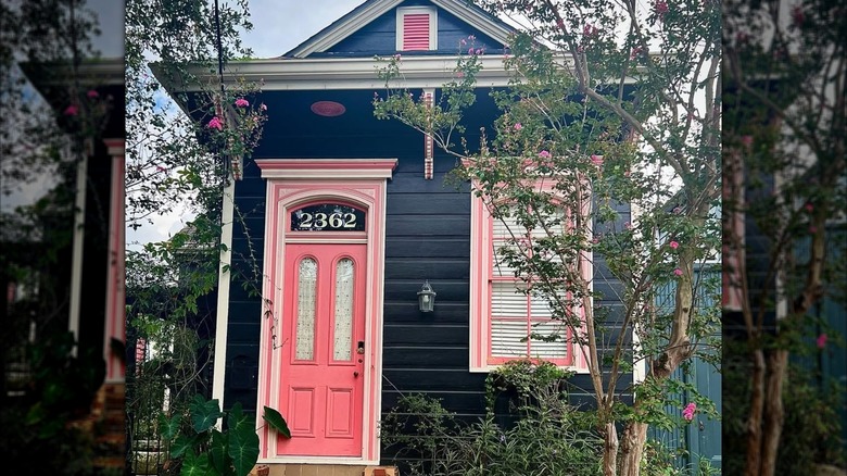 White trim and a salmon pink front door stand out against a black house