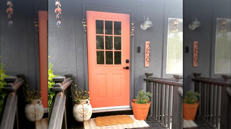 A burnt orange front door is surrounded by tribal accessories and terracotta planters