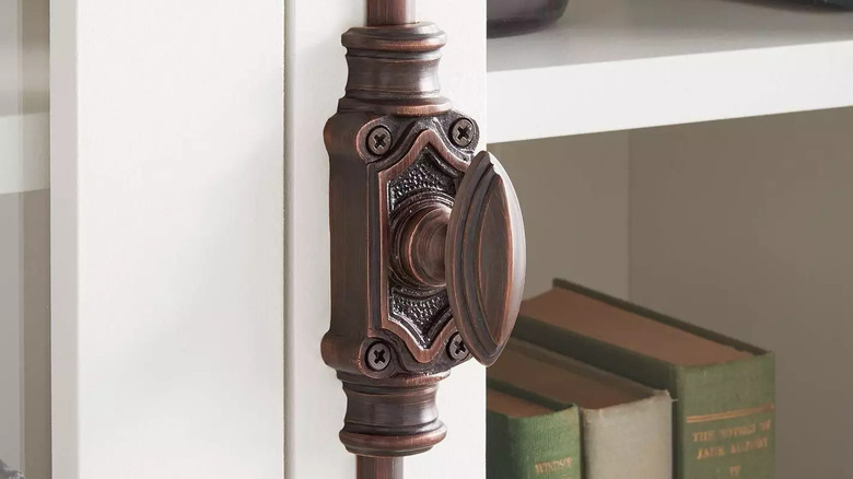 A bronze cremone bolt handle from Signature Hardware is installed on a bookshelf door