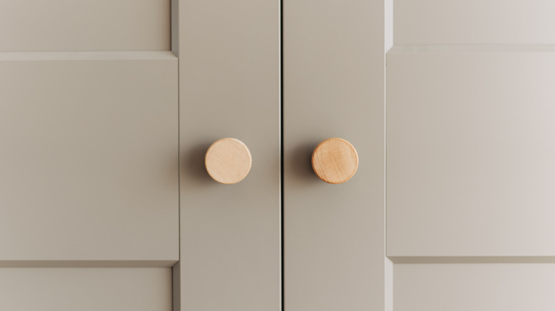 Two wooden dummy knobs are installed on a set of beige double doors