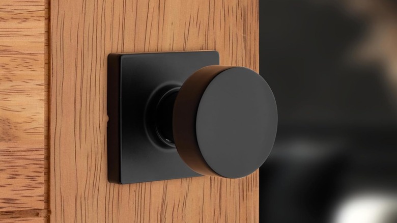 A matte black passage door knob contrasts against a wooden door