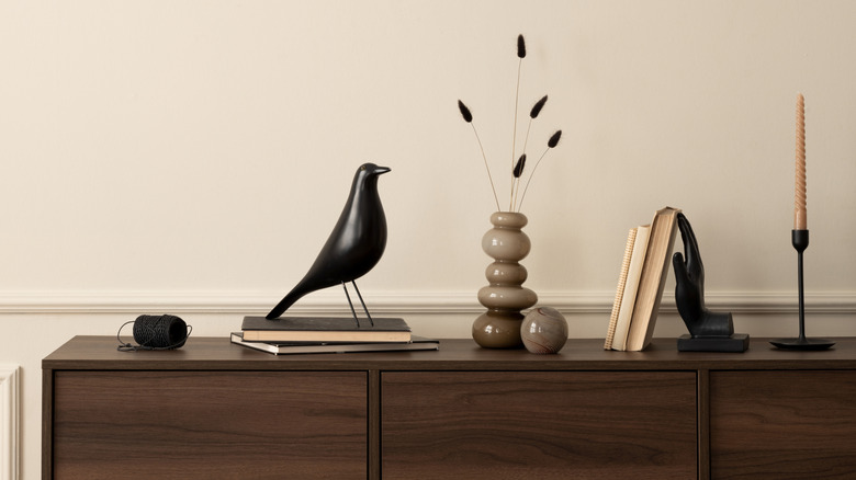 A black bird decor on a dresser stacked on top of books