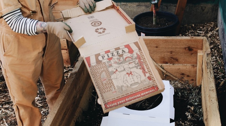Person breaking down pizza boxes and placing in garden bed