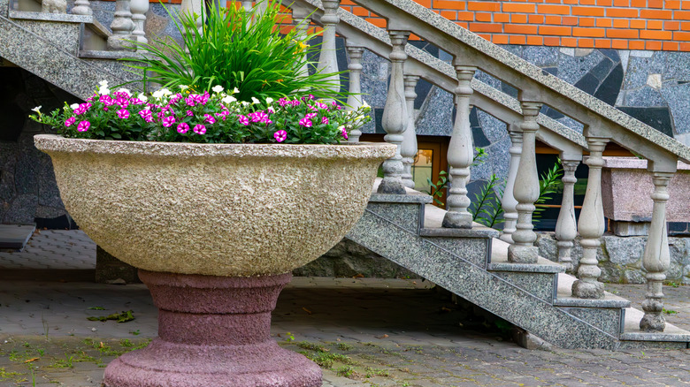 A large cement plant pot set outside in front of a staircase