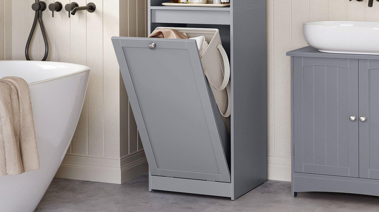 Built-in laundry hamper between a bathtub and sink