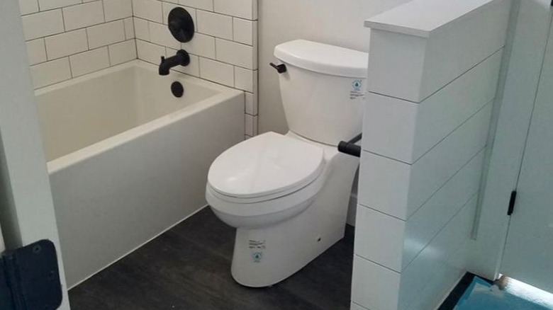 A white half wall hiding a toilet