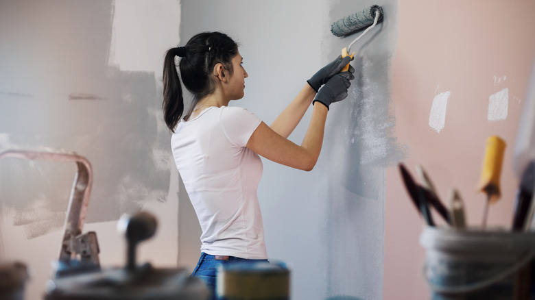 woman rolling paint on wall